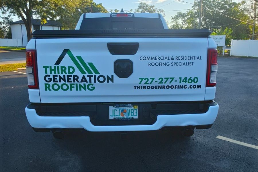 Tailgate of the RAM 1500 with the Third Generation Roofing logo, phone number and website