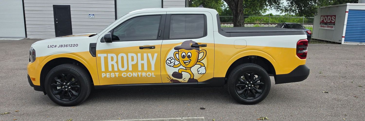 Ford Maverick with a yellow and white commercial wrap and mascot for Trophy Pest Control